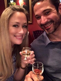 a man and woman posing for a picture holding wine glasses